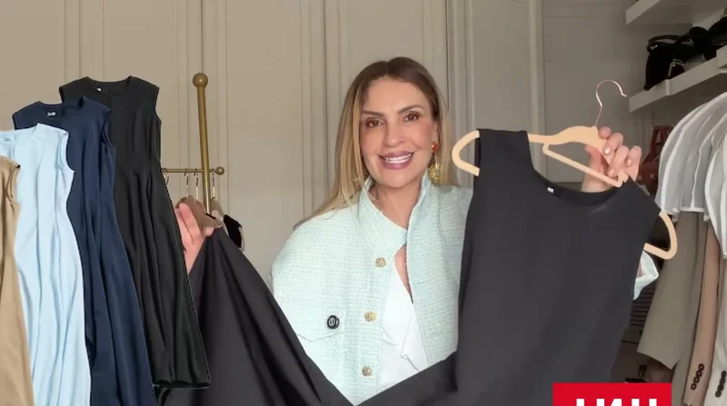Mujer sosteniendo perchas con un vestido oscuro y prendas de capa
