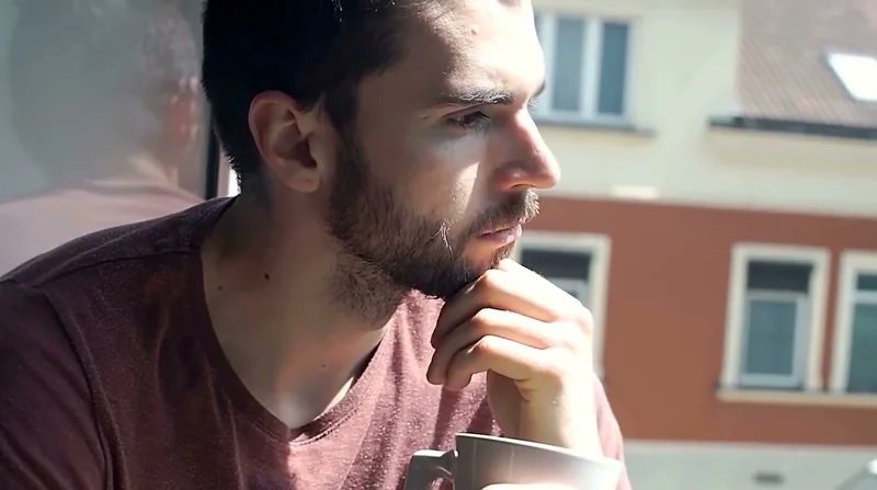 Hombre joven con gesto serio sentado en una terraza