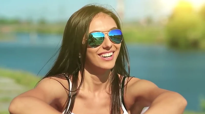 Mujer sonriente con gafas de sol al aire libre con luz de tarde